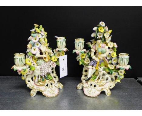 A pair of Derby figural candelabra with floral bocage and central figures, each playing a musical instrument on Rococo style 