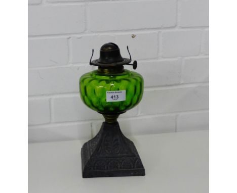 A cast metal oil lamp with green glass well