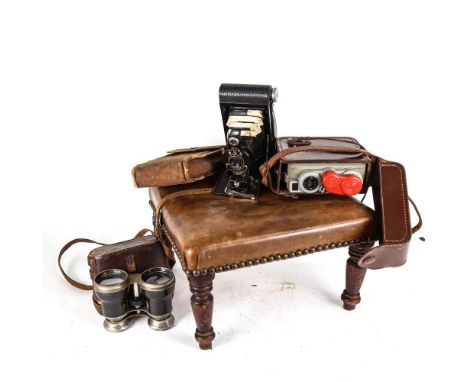 A footstool with turned wood legs, a Kodak folding camera, binoculars, and a Eumig movie camera 