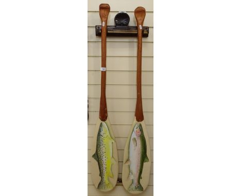 A pair of decorative painted paddles, with designs of trout, in wall-mounted bracket, by Clive Fredriksson, length 135cm 