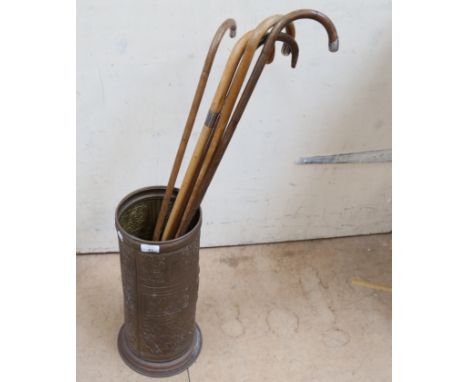 Embossed brass stick stand, containing 5 walking sticks with silver mounts