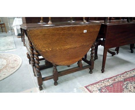 A dark oak gate leg table with barley twist legs