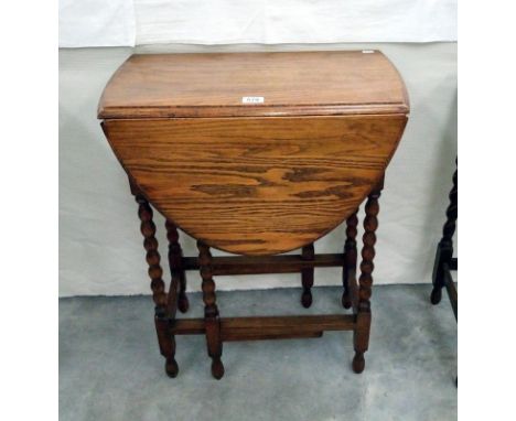 A medium oak gate leg table with barley twist legs