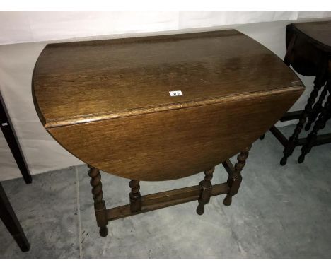 A medium oak gate leg table with barley twist legs