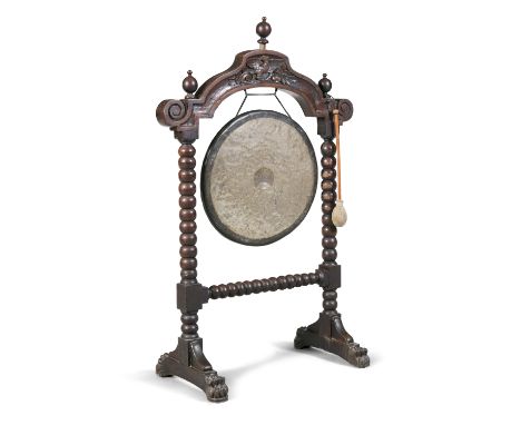 A VICTORIAN WALNUT FRAME DINNER GONG AND STAND, the arched frame decorated with a carved eagle in low relief, on bobbin turne
