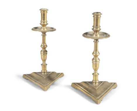 A PAIR OF 18TH CENTURY BRASS CANDLESTICKS, the ring turned stems with circular drip pans, raised on moulded heavy triangular 