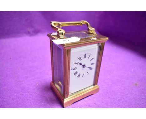 A French brass cased carriage clock having visible escape and bevel edged panels with enamel face dial