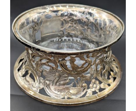 An early 20th century silver potato ring, depicting scrolling scenes of flora and fauna, clear glass liner, monogrammed, hall