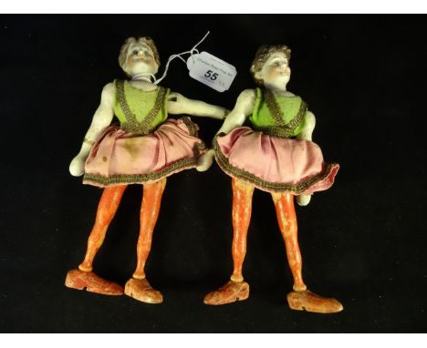Two late 19th century peg dolls, each formed of wooden bodies with ceramic heads.  Each doll similarly dressed in green and p