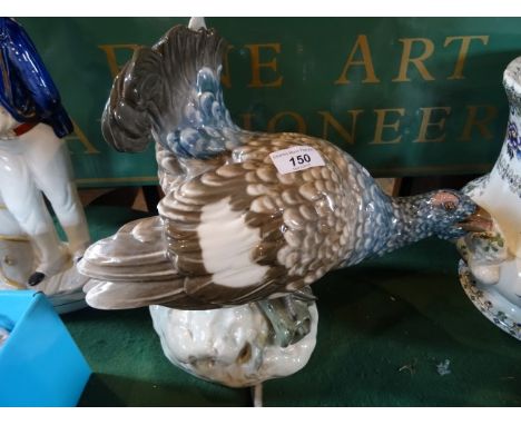 A large Continental ceramic figure of a game bird, perched on a log on rocky outcrop, printed and incise marks to base, 32cm 