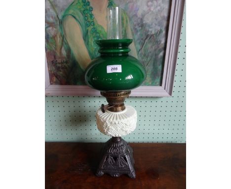 An early 20th century oil lamp, having green glass shade over opaque reservoir on square foot,  decorated with sailing ships,
