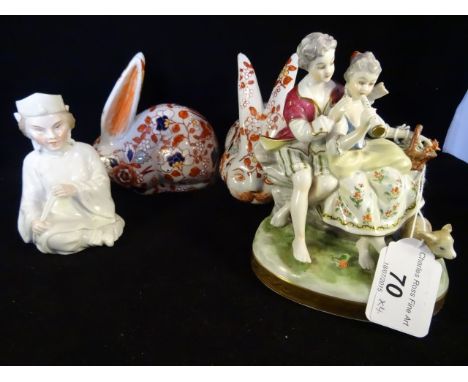 A German porcelain figure group of a couple seated on oval plinth, together with a pair of Japanese Imari ceramic rabbits, ea