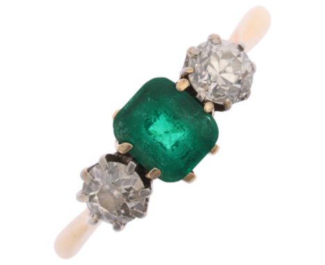 An 18ct gold three stone emerald and diamond ring, claw set with 0.7ct octagonal step-cut emerald, flanked by transitional-cu