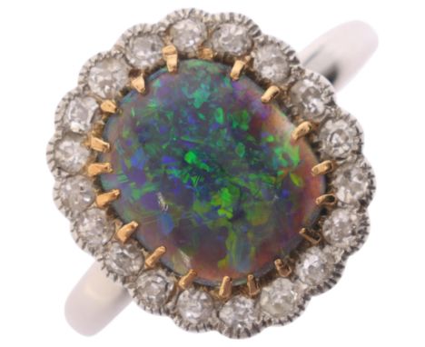 A platinum black opal and diamond cluster ring, centrally claw set with oval cabochon black opal surrounded by a row of colle