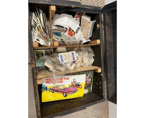 A selection of tea cards and cigarette cards in a wooden trunk 