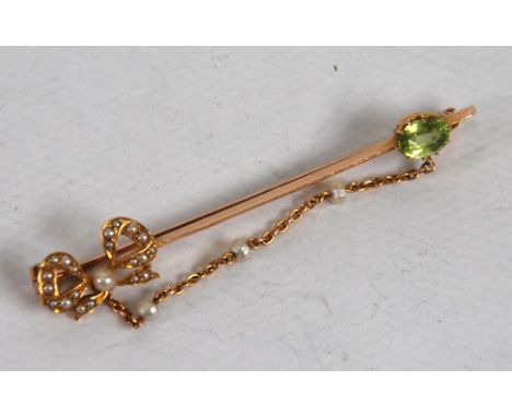 9CT GOLD BAR BROOCH with seed pearl set openwork bow at one end and oval peridot  to the other and linked with fine chain inc
