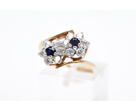 A 9CT GOLD SAPPHIRE AND CUBIC ZIRCONIA DOUBLE CLUSTER RING, designed with two asymmetrical clusters, each set with a central 