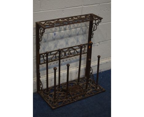 A VINTAGE WROUGHT IRON SHOE RACK, with elaborate foliate decoration, single shelf above eight wellington book racks and centr