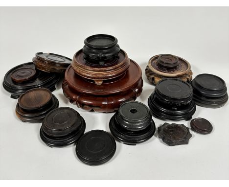 A collection of twenty various hardwood and ebonised stands and a ceramic stand, (largest d 22cm, smallest d 5cm)