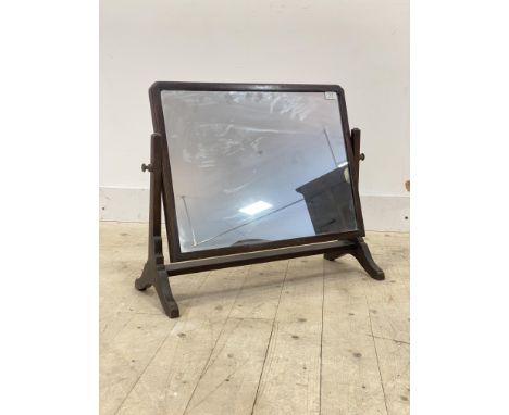 A 1930's mahogany framed vanity mirror, the rectangular plate swivelling between square tapered supports, W66cm