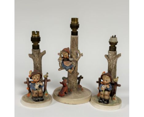 A trio of Hummel table lamps, one of a Girl sitting in a Tree with a Terrier at the base with her Shoe (h - 30cm) and a pair 
