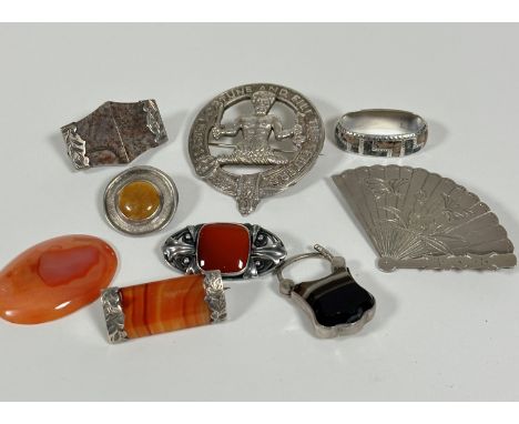 An Eastern fan shaped white metal brooch, a white metal Firth Fortune and Fill the Fetters clan style brooch, a carnelian ova