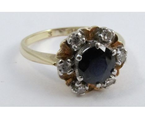 A sapphire and diamond 18 carat gold cluster ring, the round cut stone enclose by six single cut diamond points, finger size 