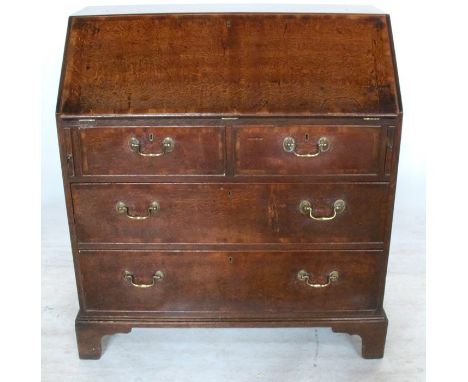 An Antique oak bureau, the fall flap opening to reveal with a cupboard, drawers and pigeon holes, over two short and two long