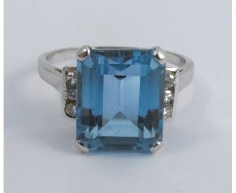 An aquamarine and diamond ring, stamped '585' to the white mount, the step cut stone 11.3 by 9.3 by 6.15mm deep, flanked eith