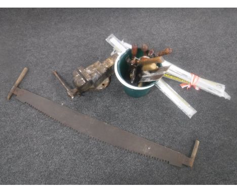 A heavy duty bench vice, vintage saw and bucket of hand tools, etc 