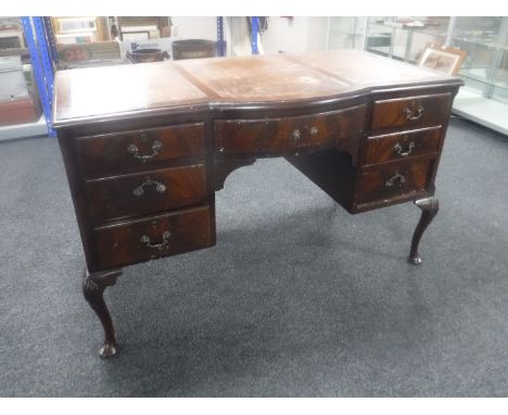 An Edwardian mahogany shaped front writing desk fitted nine drawers with brown leather tooled inset panel  CONDITION REPORT: 