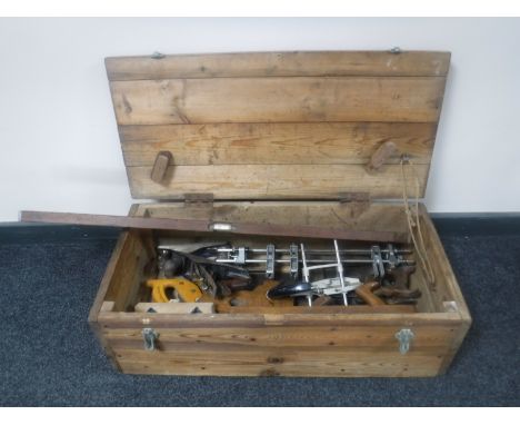 A pine crate containing vintage woodworking tools including planes, hand saw, spirit level etc