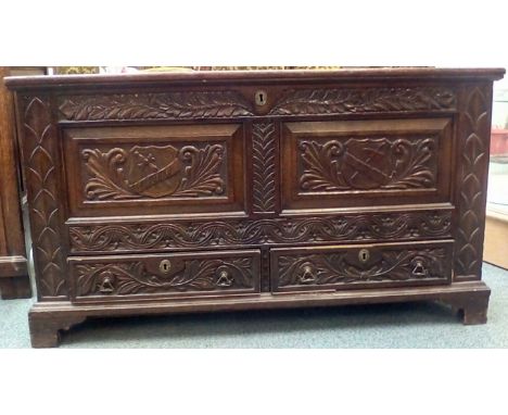 Early 19th century oak mule chest, hinged lid, carved and armorial panels over two base drawers on bracket ogee feet, height 