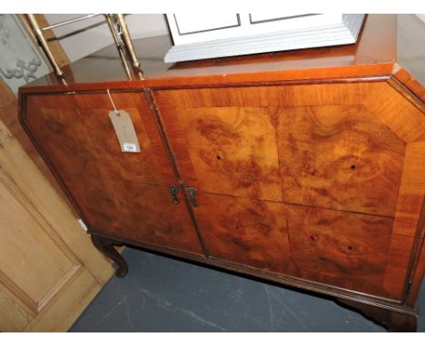 An Art Deco style walnut sideboard, the rectangular top with canted ends above an arrangement of two door enclosing drawers a