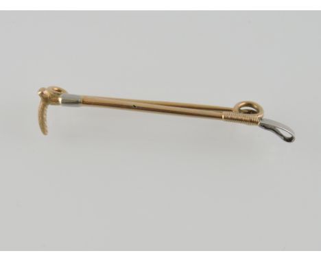 A yellow metal stick pin the the form of a riding crop, 4g