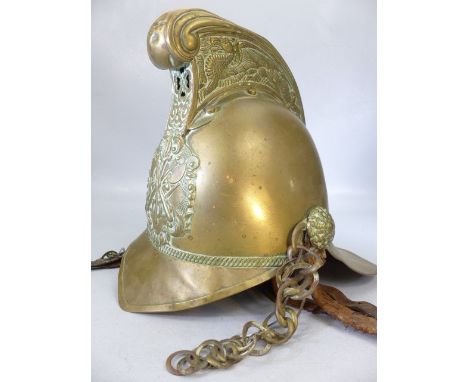 An early 20th century brass fireman's helmet.  High comb design with dragon decoration and crossed axe badge.  With leather l
