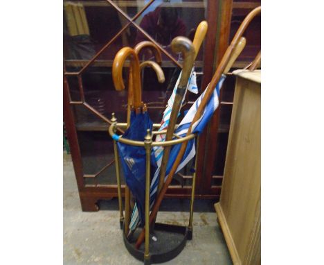 A brass demi lune stick stand containing wooden walking sticks and umbrellas Location: 