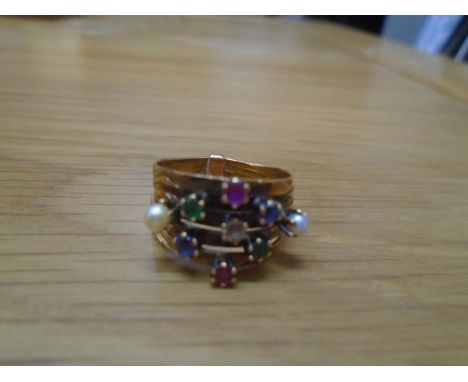 An 18k yellow gold conjoined five band ring set with emeralds, sapphires and rubies surrounding a central diamond and flanked