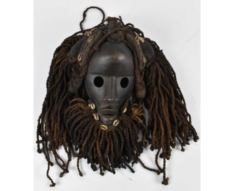 TRIBAL ART; a Dan mask with hair and beard adorned with cowrie shells, height approx 30cm.