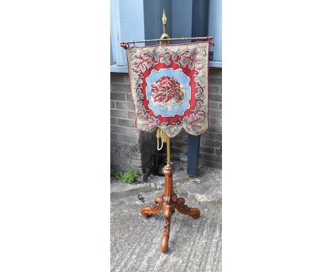 A Victorian firescreen, the beaded tapestry panel suspended from a brass rail and brass column on carved walnut tripod base, 