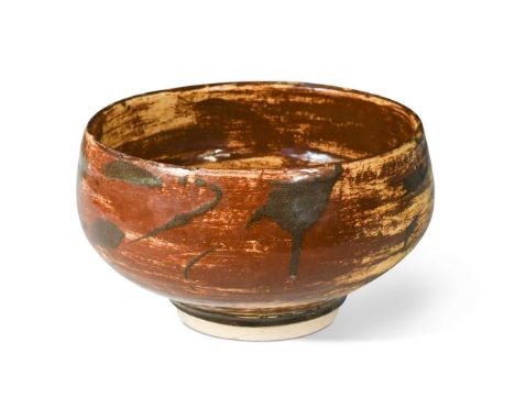 § Bernard Leach (1887-1979), an earthenware footed bowl, circa 1920s, the body slip decorated with tenmoku and persimmon over