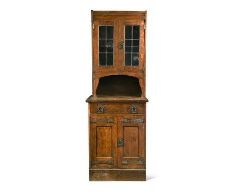 Liberty & Co., an Arts & Crafts oak narrow bookcase cabinet,  the lead glazed top section above a deep open shelf, a frieze d