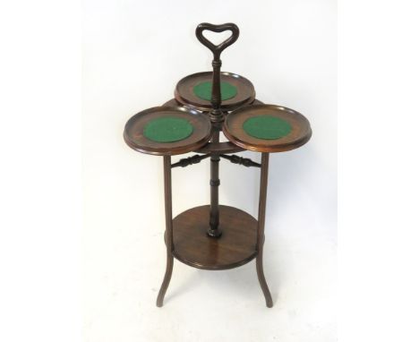 An early 20th Century cakestand
With looped handle, revolving three section top, raised on three legs with base shelf, height