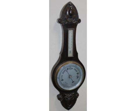 An early 20thC oak stained banjo barometer and thermometer, with silvered 20cm dia. dial in carved case surmounted by thermom