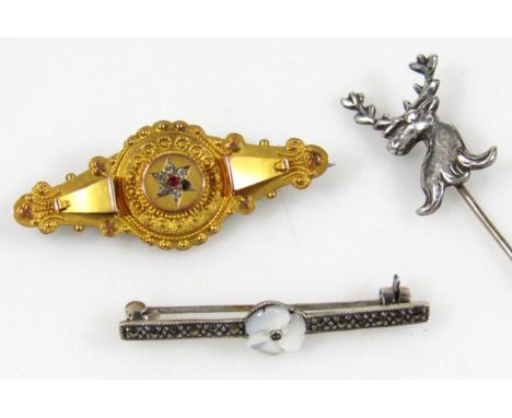 An Edwardian elipse shaped memorial brooch, centred with a small red stone in a floral arrangement, unmarked yellow metal, 5c