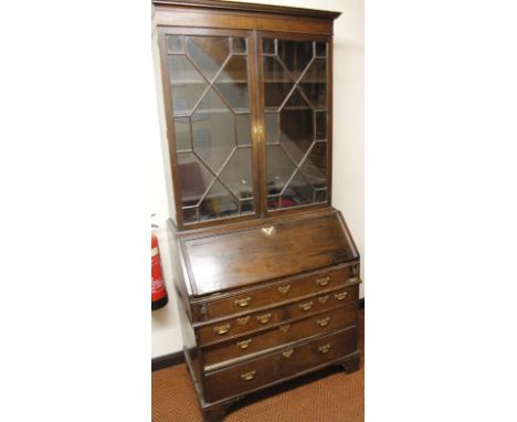 A George III and later oak bureau bookcase, the upper section with over hanging moulded cornice, above a pair of astragal gla