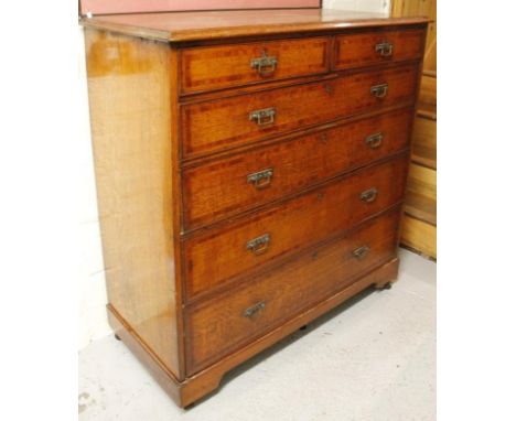 An Edwardian oak chest, of large proportion, the over hanging moulded top raised above two short and four long graduated draw