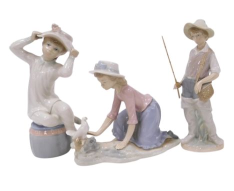 A Lladro porcelain figure of a boy fisherman, another of a boy seated on a pouffe wearing a bonnet, and a Nao figure of a gir