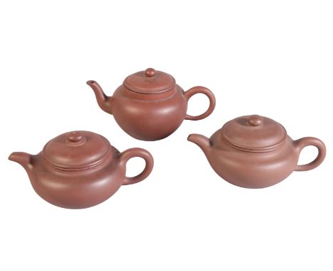 A GROUP OF THREE CHINESE YIXING TEAPOTS one with an incised mark to the inside of the lid, 11cm high, one with a seal mark to