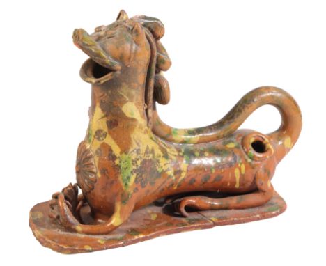 A CANNAKALE POTTERY RECUMBENT LION EWER 19th century, Turkish, Ottoman, daubed with green and yellow glaze, 19cm high x 24cm 